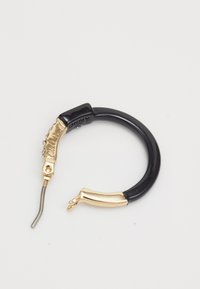 Boucle d'oreille noire et dorée avec un fermoir en métal courbé et des détails dorés texturés d'un côté.