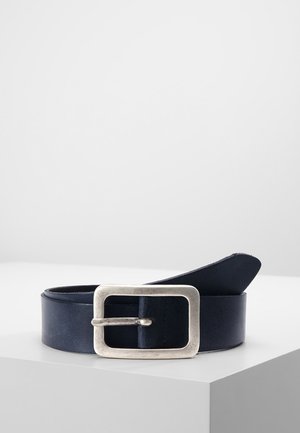 Ceinture en cuir bleu marine foncé avec une boucle en métal argenté rectangulaire reposant enroulée sur une surface blanche avec un fond uni.