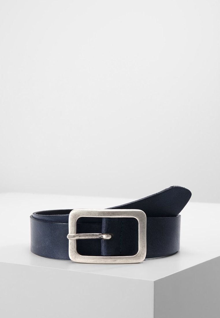 Ceinture en cuir bleu marine foncé avec une boucle en métal argenté rectangulaire reposant enroulée sur une surface blanche avec un fond uni.