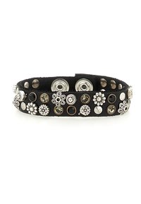Bracciale in pelle nera decorato con borchie floreali metalliche e strass. Presenta chiusure a scatto e una superficie liscia e texturizzata.