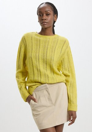Pull en laine jaune avec des rayures verticales, coupe décontractée, encolure ronde et texture douce, assorti d'une jupe en corduroy beige avec des poches.