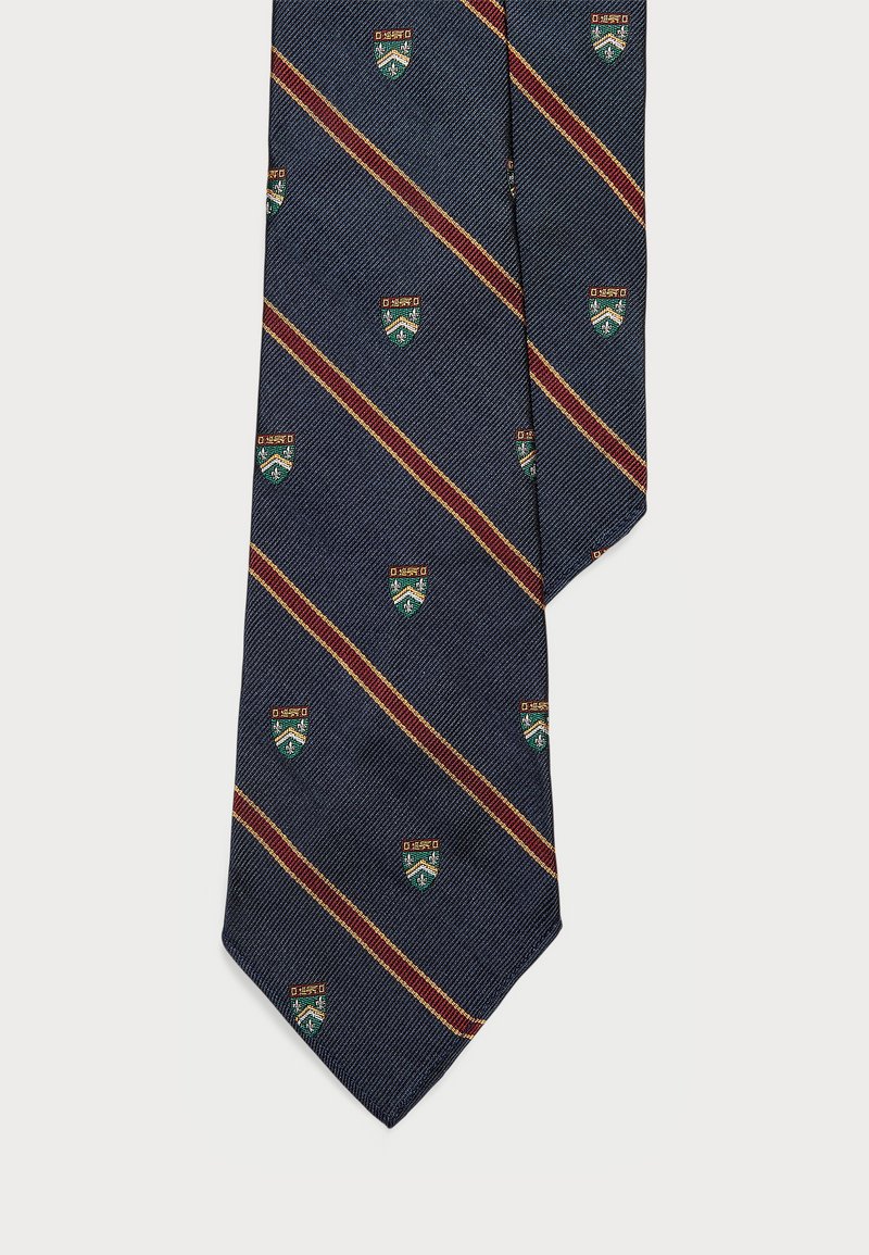 Σκούρο μπλε γραβάτα με διαγώνιες μπορντό ρίγες; διαθέτει μικρά, εναλλασσόμενα πράσινα και χρυσά μοτίβο με ασπίδες; υφή υφάσματος.