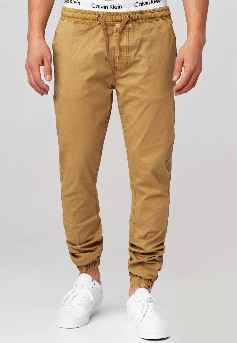 Pantalones jogger color arena con cintura elástica y cordón, que cuentan con puños elásticos en los tobillos. Fabricados en tejido suave, con bolsillos laterales.