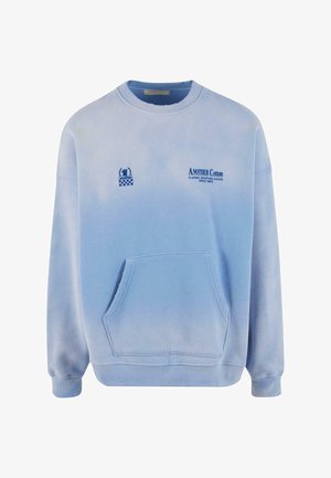 Šviesiai mėlynas medvilninis džemperis su priekiu kišenėle, burbuliuotais rankogaliais ir išsiuvinėtais logotipais kontrastinga mėlyna spalva. Sklandus audinys su gradientiniu atspalviu.