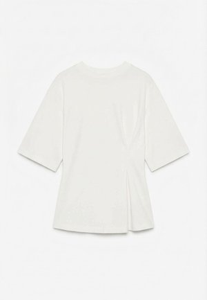 Camiseta blanca de manga corta con cuello redondo y un sutil detalle de pliegue en el lado derecho, mostrada estirada sobre un fondo blanco.