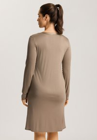 Vestido de manga larga y largo hasta la rodilla en suave tela color marrón claro. Presenta un cuello redondo y un corte relajado con detalles mínimos.