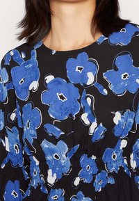 Floral-printed dress features large blue and white flowers on a black background, with elastic detailing at the waist and a round neckline.