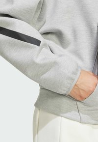 Γκρι φούτερ με υφή, featuring μια μαύρη ρίγα στο μανίκι και μια τσέπη, έχει εφαρμοστή σχεδίαση και ribbed τελείωμα.