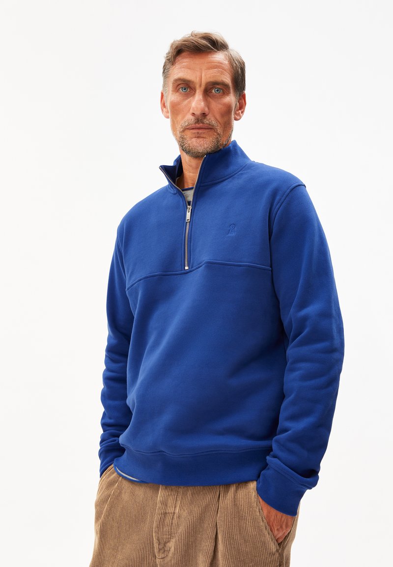 Blauwe fleece pullover met een kwart-rits kraag, ribbels aan de mouwen en een naaddetail op de borst. Textiel met een zachte afwerking.