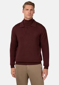 Maglione a maglia bordeaux con collo alto e colletto aperto. Caratterizzato da polsini e orlo a costine. Texture liscia con una forma rilassata.