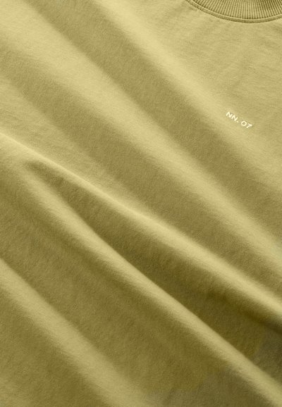 Olivgrön bomulls t-shirt med en mjuk textur, rundad halsringning och liten vit text "NN. 07" fram. Minimalistisk design.
