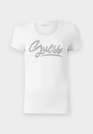 Witte T-shirt met korte mouwen en ronde hals, met 'Guess' in cursieve letters en glinsterende zilveren versieringen op de borst.
