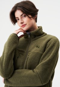 Fleecejacke in Olivgrün mit hohem Kragen, Frontreißverschluss, zwei Brusttaschen und strukturierter Stoff. Details umfassen ein Logo auf der Brust.
