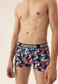 Kolorowe bokserki z geometrycznymi wzorami w niebieskim, czerwonym i kremowym kolorze. Posiadają czarny pas z napisem "HENDERSON" w jasnym foncie.