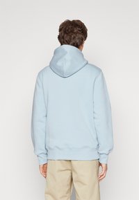 Light blue hoodie made of soft fabric. Features a large hood, roomy sleeves, and ribbed cuffs and hem. Simple, solid color without patterns.