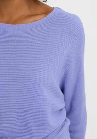 Pull en tricot lilas avec un large col, tissu texturé, manches longues et coupe décontractée. Présente un subtil motif côtelé sur l'ensemble.