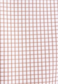 Tessuto di cotone in un modello a scacchi bianco e marrone chiaro. Il design presenta quadrati di dimensioni uniformi con una finitura strutturata.