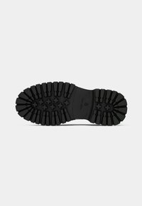 Black rubber shoe sole featuring deep treads and cross patterns for traction. Smooth edges with a sturdy design for durability.