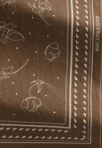 Braun gemusterter Schal mit weißen Blumenlinien, gepunkteten Akzenten und dekorativem Rand mit linearen Details. Markenname "Marco Polo Denim".