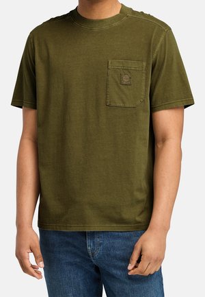 Homme portant un t-shirt à manches courtes vert olive avec poche poitrine et jean bleu, cadré au niveau du cou et mi-cuisse.