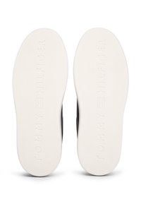 Čierna teniska s hladkým zvrškom a textúrovanou bielou gumovou podrážkou. Má vyrazené logo "TOMMY HILFIGER" a vzor na lepšiu trakciu.