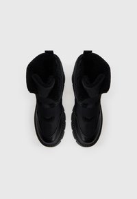 Fekete téli csizmák texturált szörme béléssel, tartós külső anyaggal és rugalmas pántokkal a szárnál a biztos illeszkedés érdekében. Kerek orrú kialakítás.