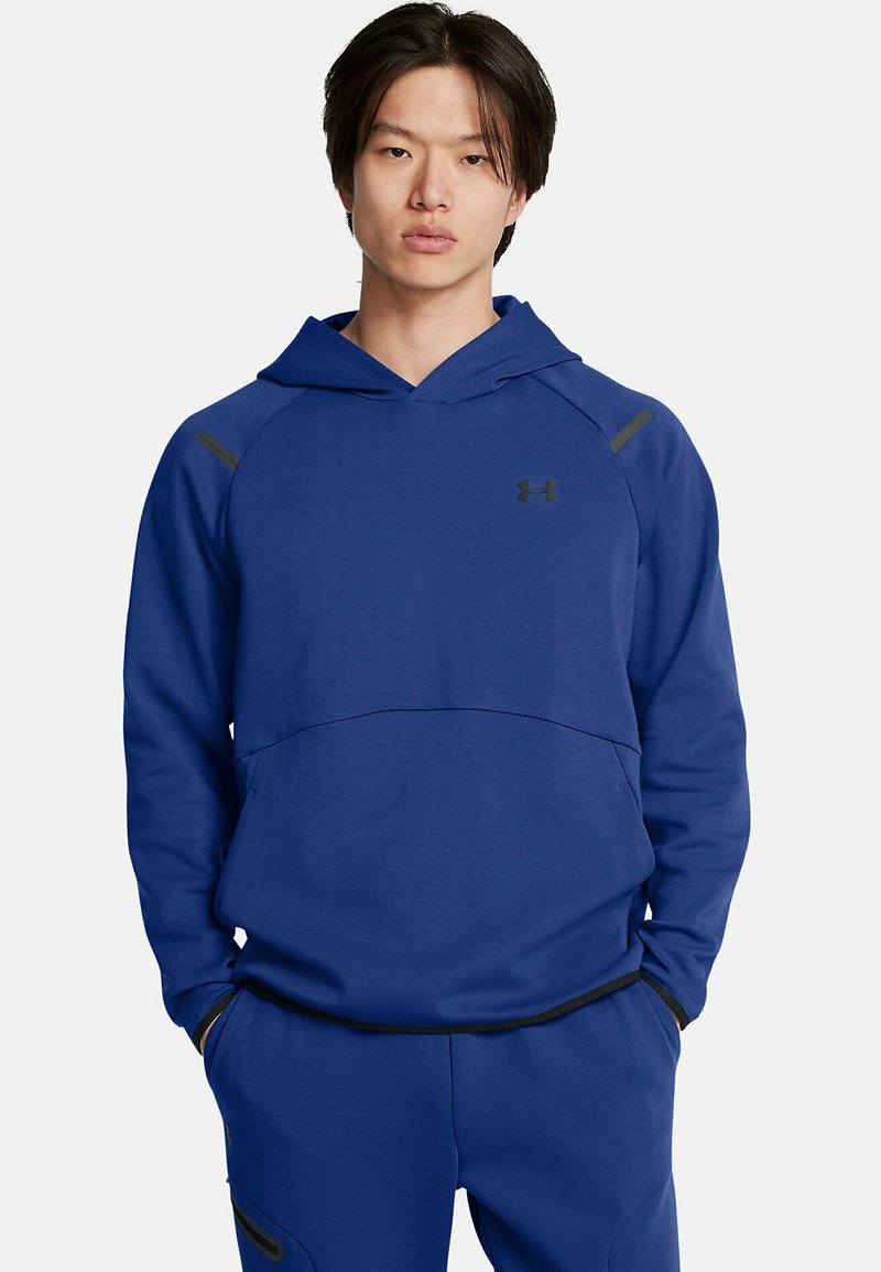Sudadera azul marino con un bolsillo tipo canguro, acentos negros en los hombros, un escote amplio y un logo sutil en el pecho. Textura de tela suave.