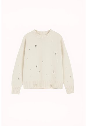 Bézs hosszú ujjú kötött pulóver kopott, szakadt lyukakkal az elején, az ujjakon, valamint a bordázott szegélyen és mandzsettákon.