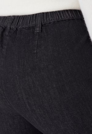 Mallas de mezclilla negras con una cintura elástica, con una textura suave y un ligero brillo. Sin costuras ni patrones visibles.
