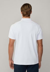 Hvid bomulds polo-shirt med krave og korte ærmer, som har en glat overflade og en lige kant. Bagsiden har ingen yderligere designs.