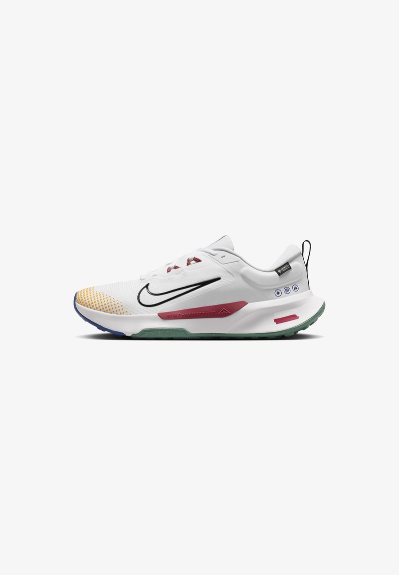 Baskets blanches de sport avec le Swoosh Nike noir, bout jaune à pois, accents rouges, semelle verte et languette noire au talon.