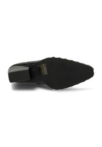 Suela de zapato negro de tacón alto con una superficie texturizada, que presenta un tacón de bloque y acentos de placa de metal. Instrucciones de cuidado grabadas visibles.