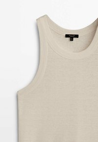 Beige tanktop gemaakt van lichtgewicht, ribbelstof met een ronde halslijn en brede armsgaten. Bevat een verzorgingslabel dat aan de achterkant is gestikt.