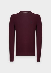 Pull en tricot bordeaux à manches longues, texture côtelée, et encolure ronde. Petit logo sur la poitrine gauche.