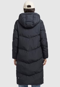 Cappotto imbottito lungo di colore grigio scuro con cappuccio. Presenta cuciture a zig-zag e tasche laterali. Realizzato in materiale leggero e isolante.