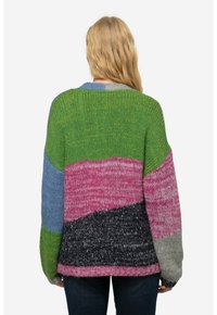 Monivärinen neulepaita, jossa on vihreitä, vaaleanpunaisia, sinisiä, harmaita ja mustia osioita. Löysä istuvuus, leveät hihat ja ribbitekstuuri.