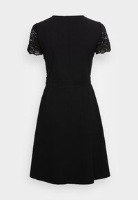 Svart klänning med figursydd midja, utställd kjol och korta ärmar i spets. Enkel rund halsringning och ren, slät tygtextur.