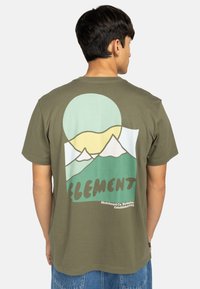 Olivenfarbenes Baumwoll-T-Shirt mit einem Grafikdesign von Bergen und Sonne in gedämpften Farben. Der Text "ELEMENT" befindet sich am unteren Rand mit Logodetails.