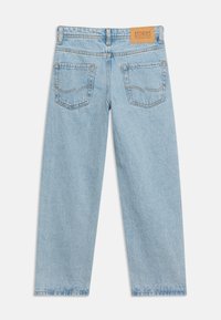 Τζιν σε ελαφρύ μπλε χρώμα με ίσια γραμμή, εμφανιζόμενο από πίσω, με δύο πίσω τσέπες και ένα ταμπελάκι από δέρμα σε καφέ χρώμα στη μέση.