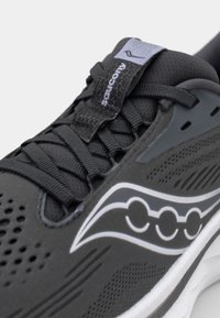 Baskets de course noires avec une tige en maille à perforations, semelle blanche épaisse, et un accent de logo gris sur le côté et la languette.