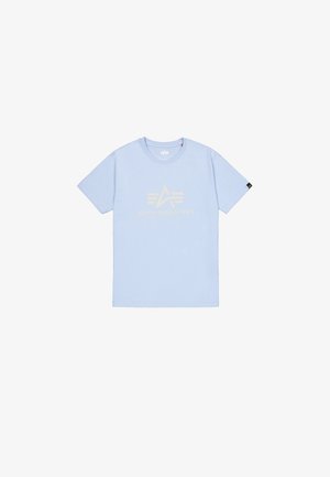 Világoskék pamut póló, arany "ALPHA INDUSTRIES" logóval és háromszög alakú grafikai dizájnnal az elején. Rövid ujjú, kerek nyakú.