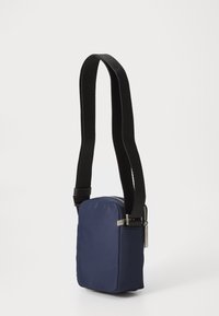 Borsa a tracolla blu navy realizzata in tessuto morbido, con forma rettangolare, tracolla nera regolabile e chiusura con zip argentata.