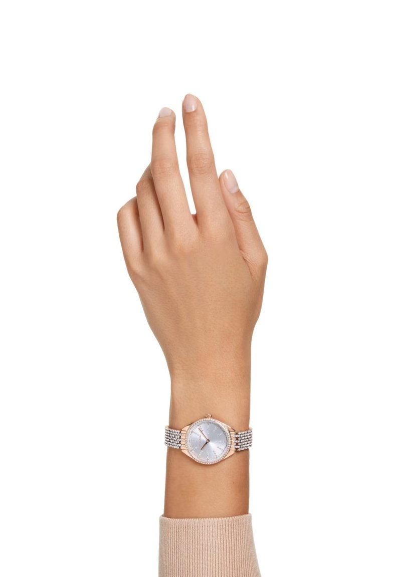 Roze gouden horloge met een octagonale kast, zilveren wijzerplaat en een band met kristalaccenten. De wijzer staat omhoog, waardoor de details van het horloge goed zichtbaar zijn.