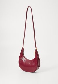 Burgundy leather handbag with a curved shape, a single strap, and gold-tone hardware. Features a zip closure and textured surface.