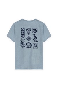 Camiseta de color azul claro con un diseño detallado en marino que presenta motivos botánicos y animales, incluyendo flores, una garza y jarrones en varias formas.