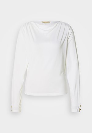 Fehér, hosszú ujjú póló kerek nyakkivágással, vállnál összegyűrt részletekkel és aranyszínű gombdíszítéssel az ujjakon. Puha, sima tapintású anyag.