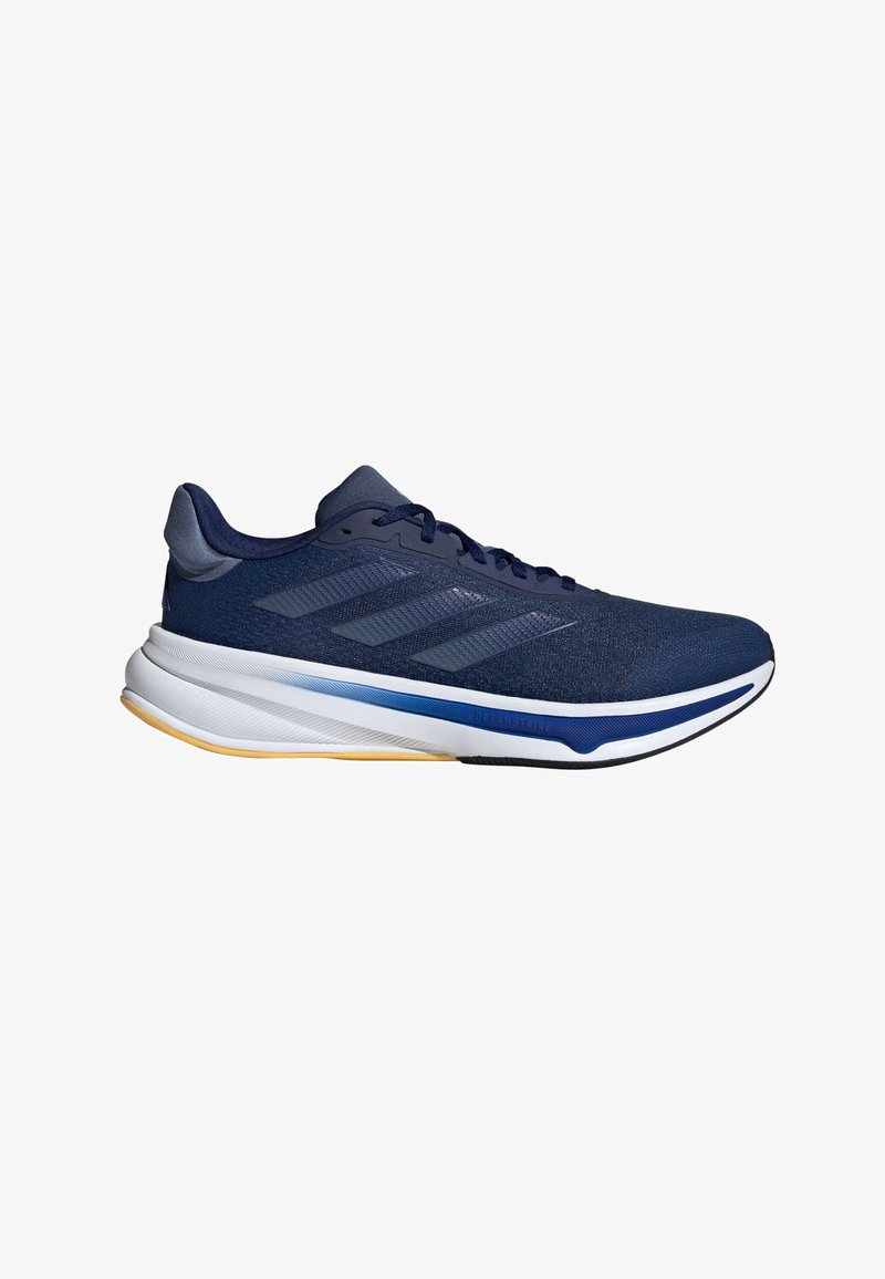 Chaussure de course bleu marine avec trois bandes, semelle coussinée blanche et bleue, et semelle extérieure marron clair, vue de côté.