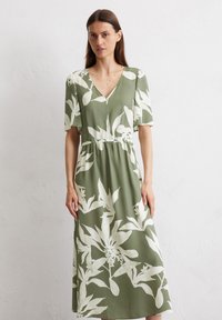 Vestito floreale verde realizzato in tessuto leggero, con scollo a V, maniche corte, vita elastica e grande stampa bianca di piante.