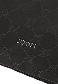 Pochette nera con zip, decorata con un motivo testurizzato di fiori stilizzati. Logo "JOOP!" in accento metallico argento sul davanti. Materiale resistente.