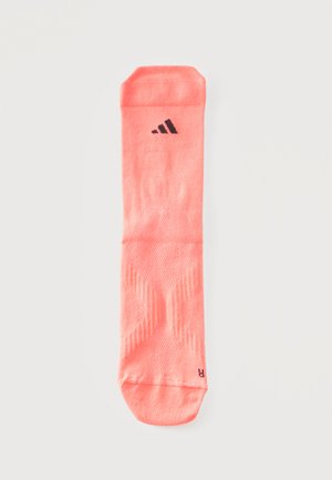 Chaussette de sport unique couleur corail avec un logo Adidas noir près du haut, texture côtelée et un "R" indiquant qu’elle est destinée au pied droit.